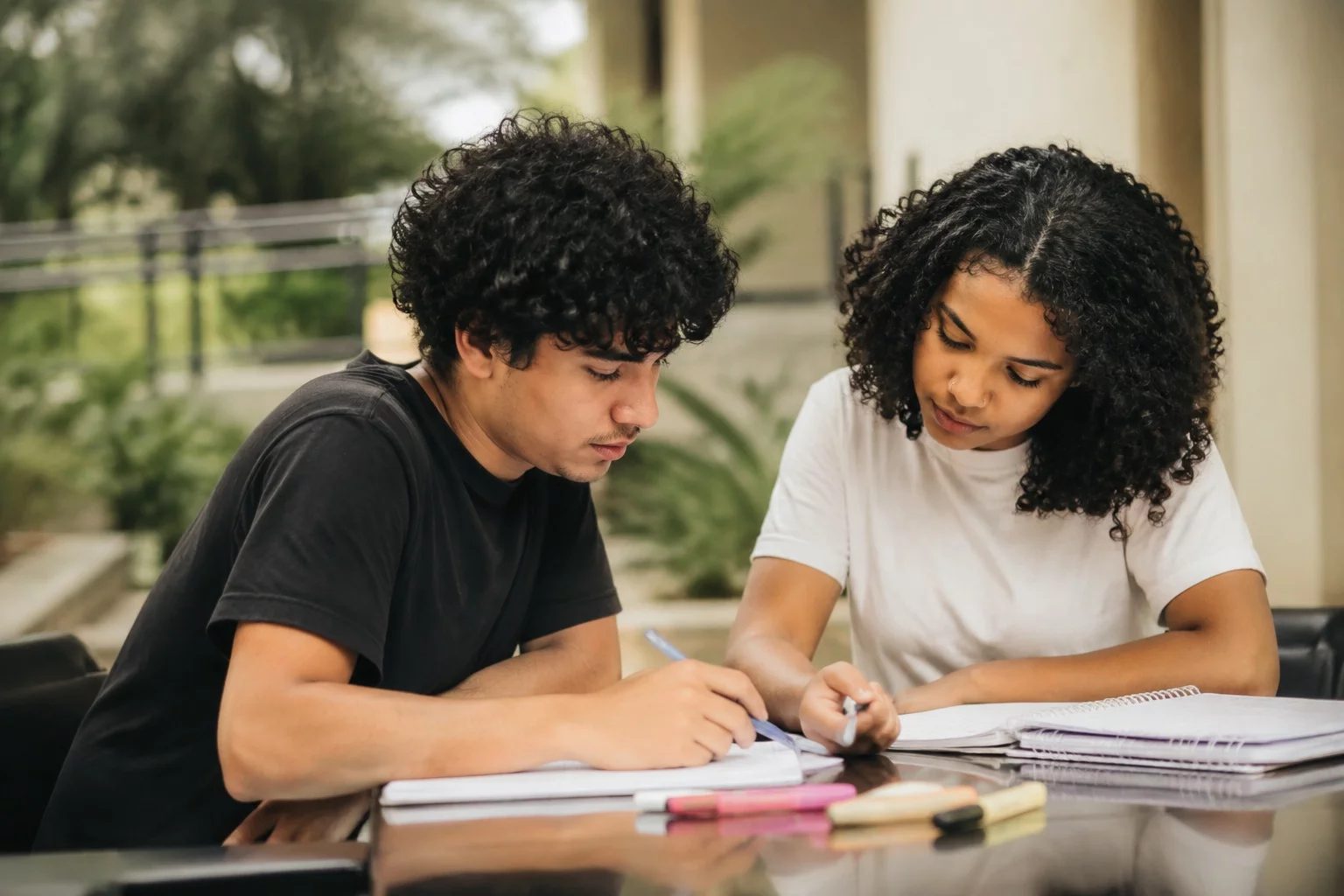 Dois estudantes preparando um debate com cadernos e marcadores