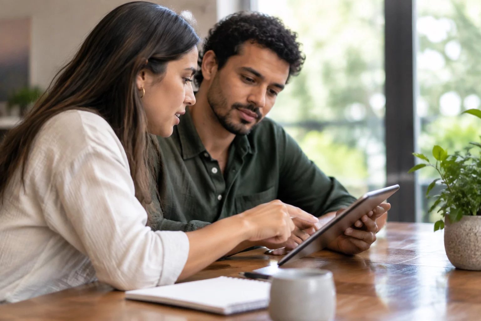 Duas pessoas revisando anotações em um tablet sobre uma mesa de madeira
